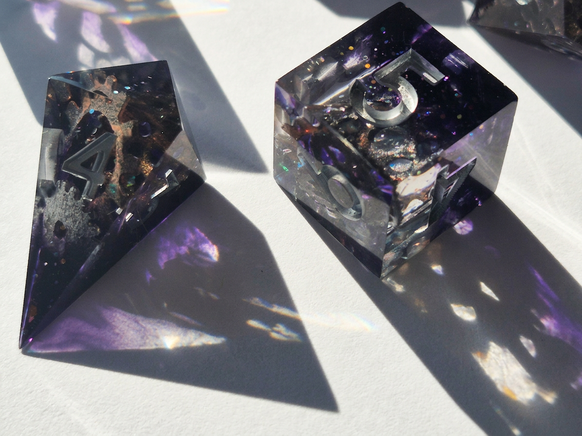A selection of gear-shaped inclusions in clear resin with a smoky purple backing on a white table surface.